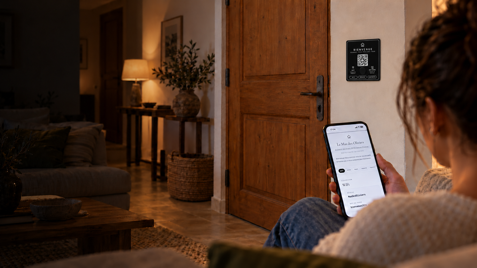 Une voyageuse consulte le guide Hoteya près d’une plaque connectée dans un logement